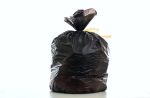 Trash, garbage bag black color full with litter and tied isolated against white background